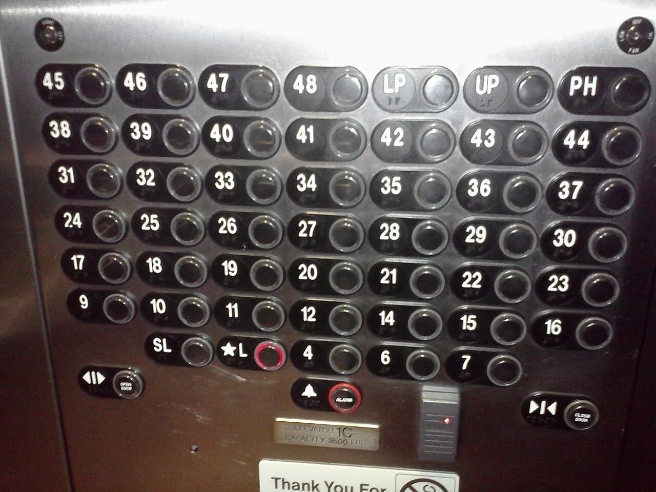 An elevator panel with dozens of buttons and codes like LP, UP and SL.